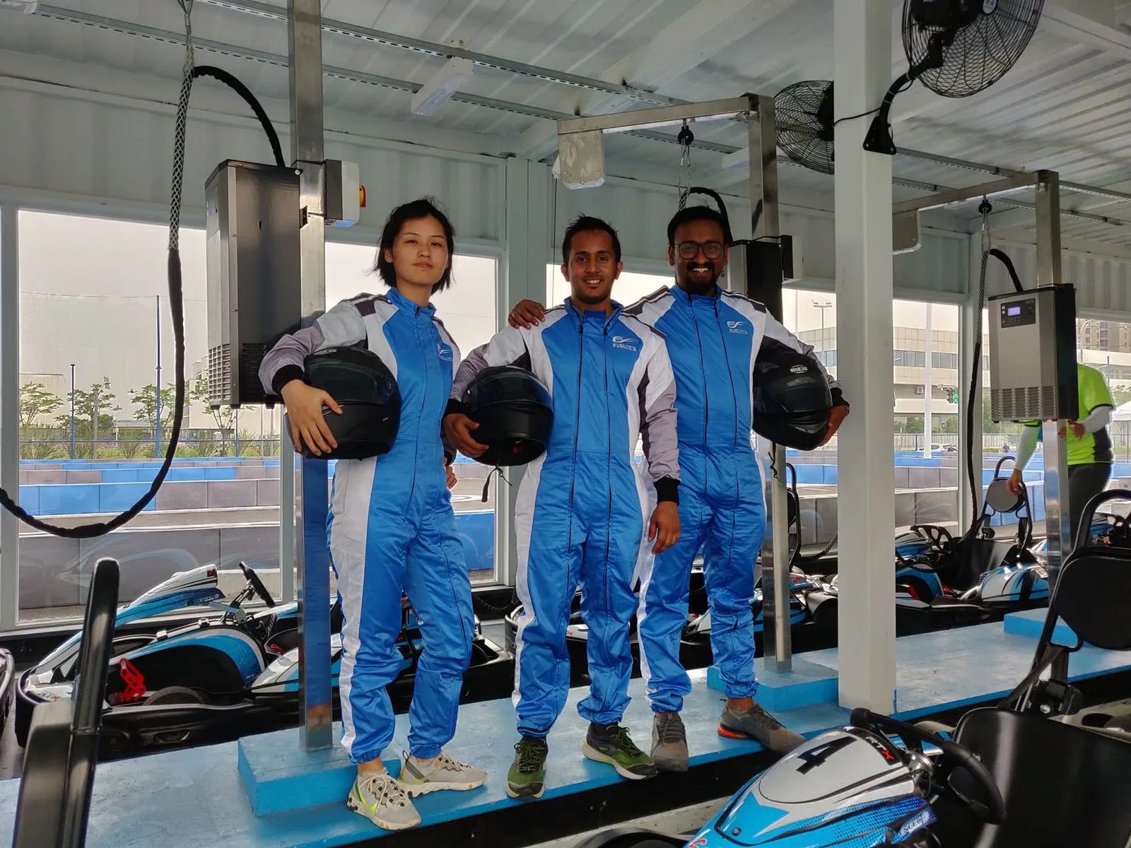 Raj and friends in racing suits at a karting track